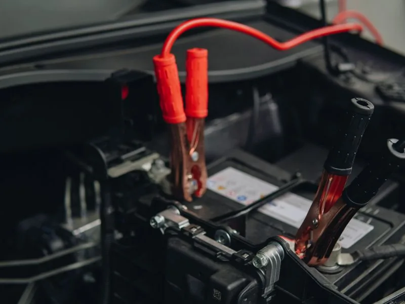 Jumper cables connected to a car battery during a jump start